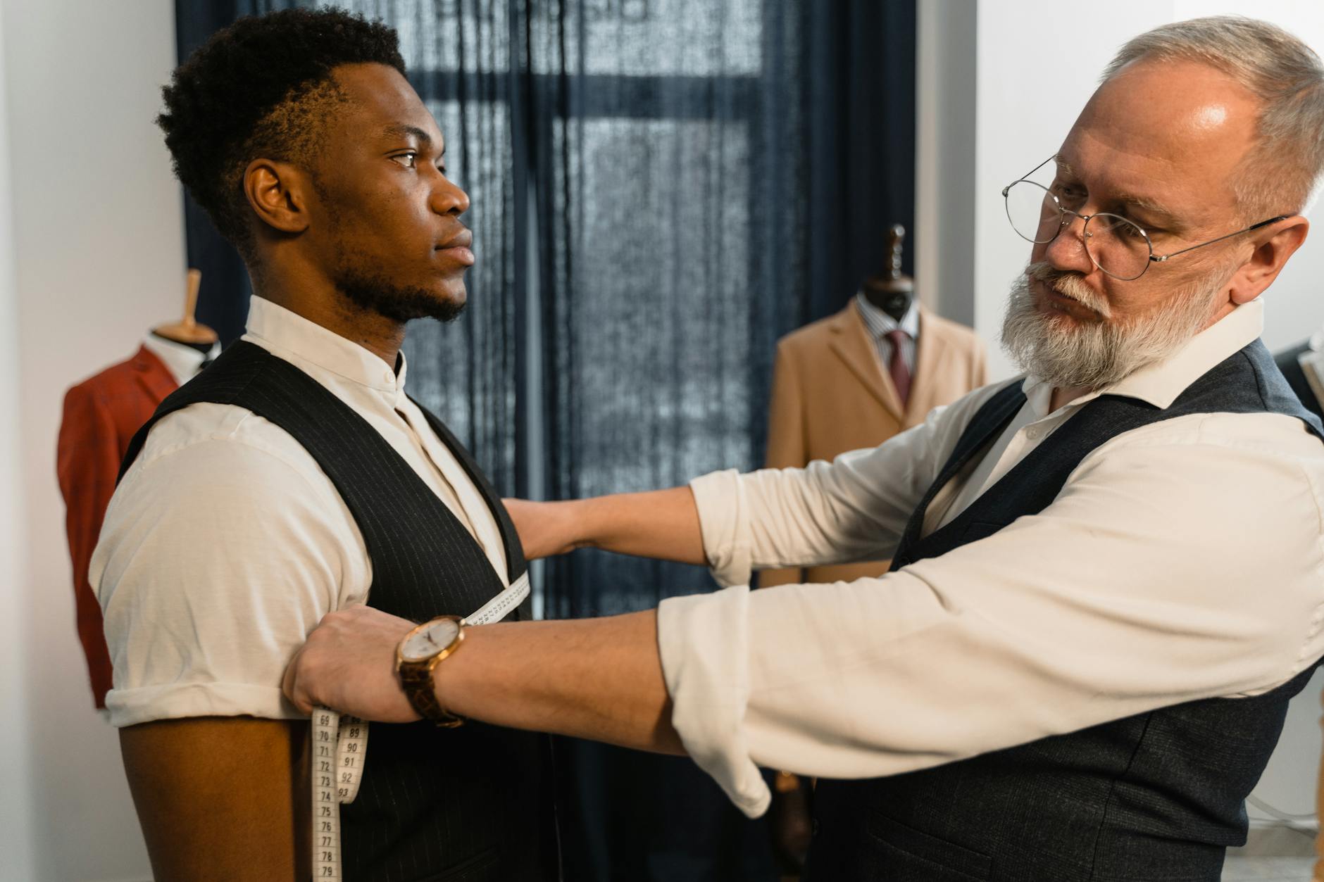 Krawiec mierzy klienta podczas przymiarki garnituru w pracowni