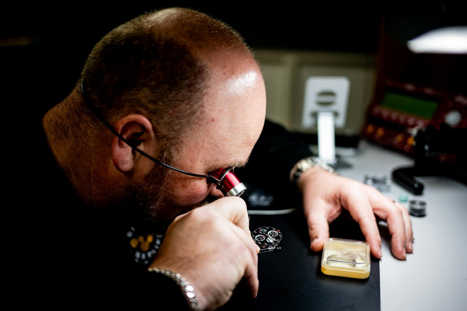 Rzemieślnik z lupą dokładnie ogląda mechanizm eleganckiego zegarka