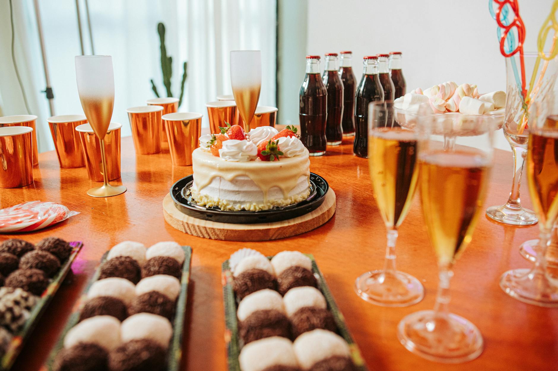 Stół z tortem, kolorowymi drinkami i deserami na domowej imprezie