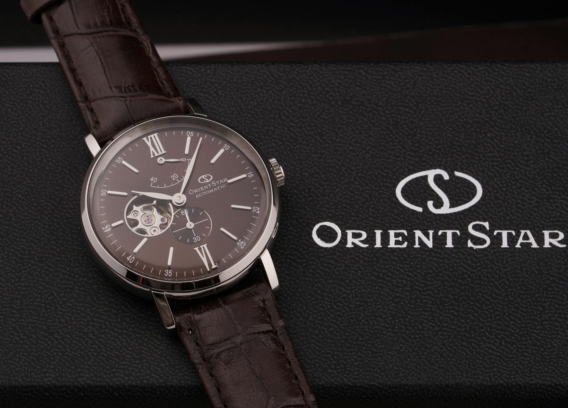 Zbliżenie eleganckiego zegarka Orient Star z brązowym paskiem na pudełku