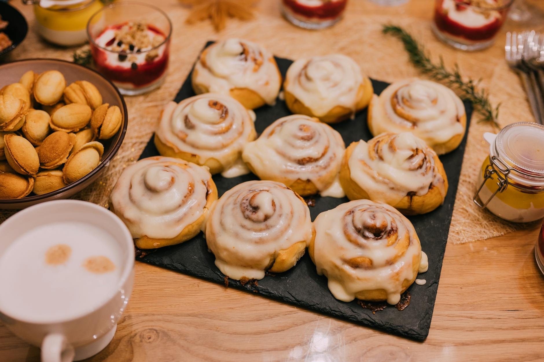 Cynamonowe bułeczki drożdżowe z lukrem serowym na śniadaniowym talerzu