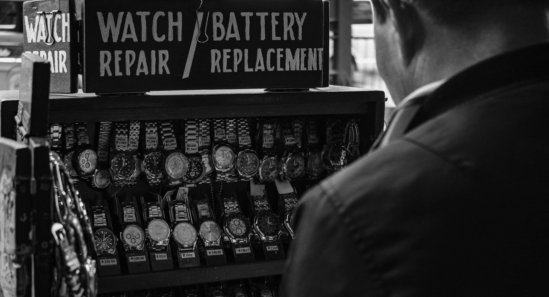 Czarno-białe stoisko zegarmistrza z kilkoma zegarkami na pasku