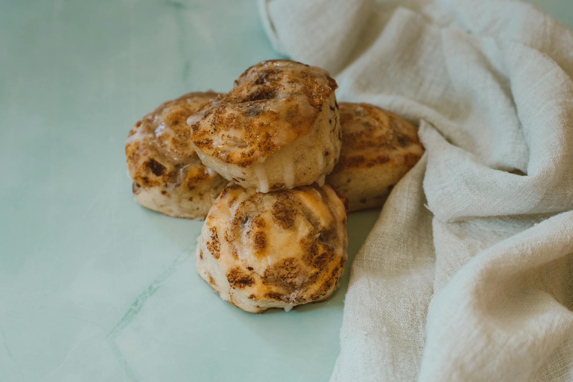 Domowe drożdżowe bułeczki cynamonowe z lukrem na marmurowym blacie