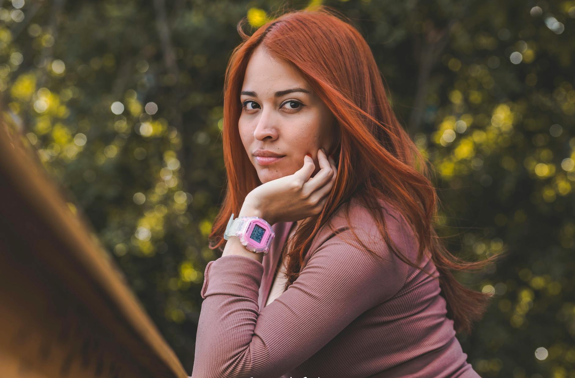 Kobieta w różowym swetrze z dużym zegarkiem na nadgarstku na zewnątrz