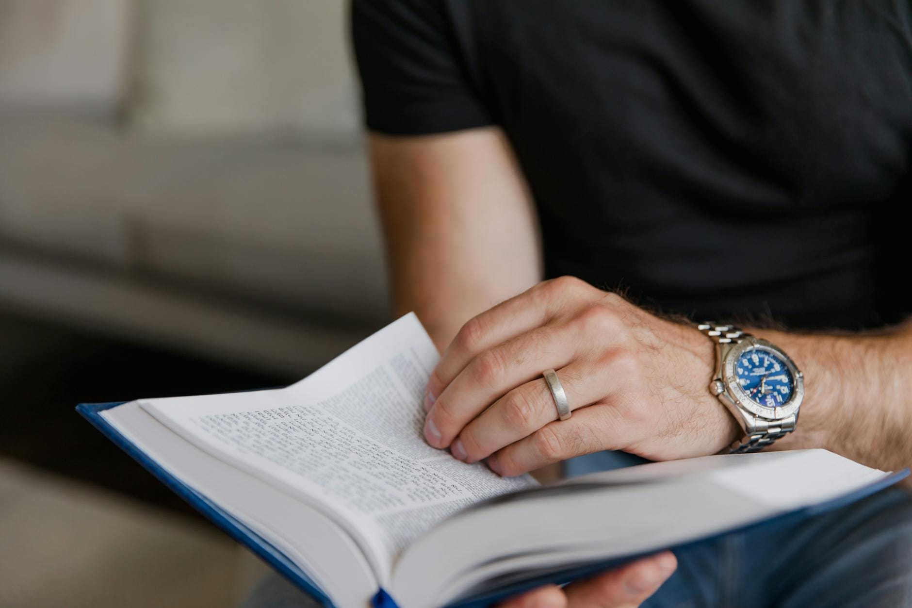 Męska dłoń z zegarkiem sportowym trzymająca otwartą książkę