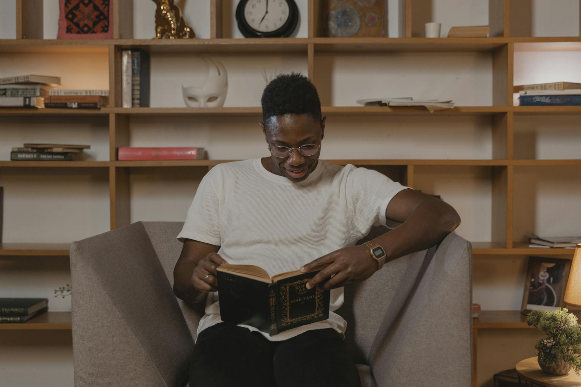 Mężczyzna w nowoczesnym salonie czytający książkę na tle drewnianych półek