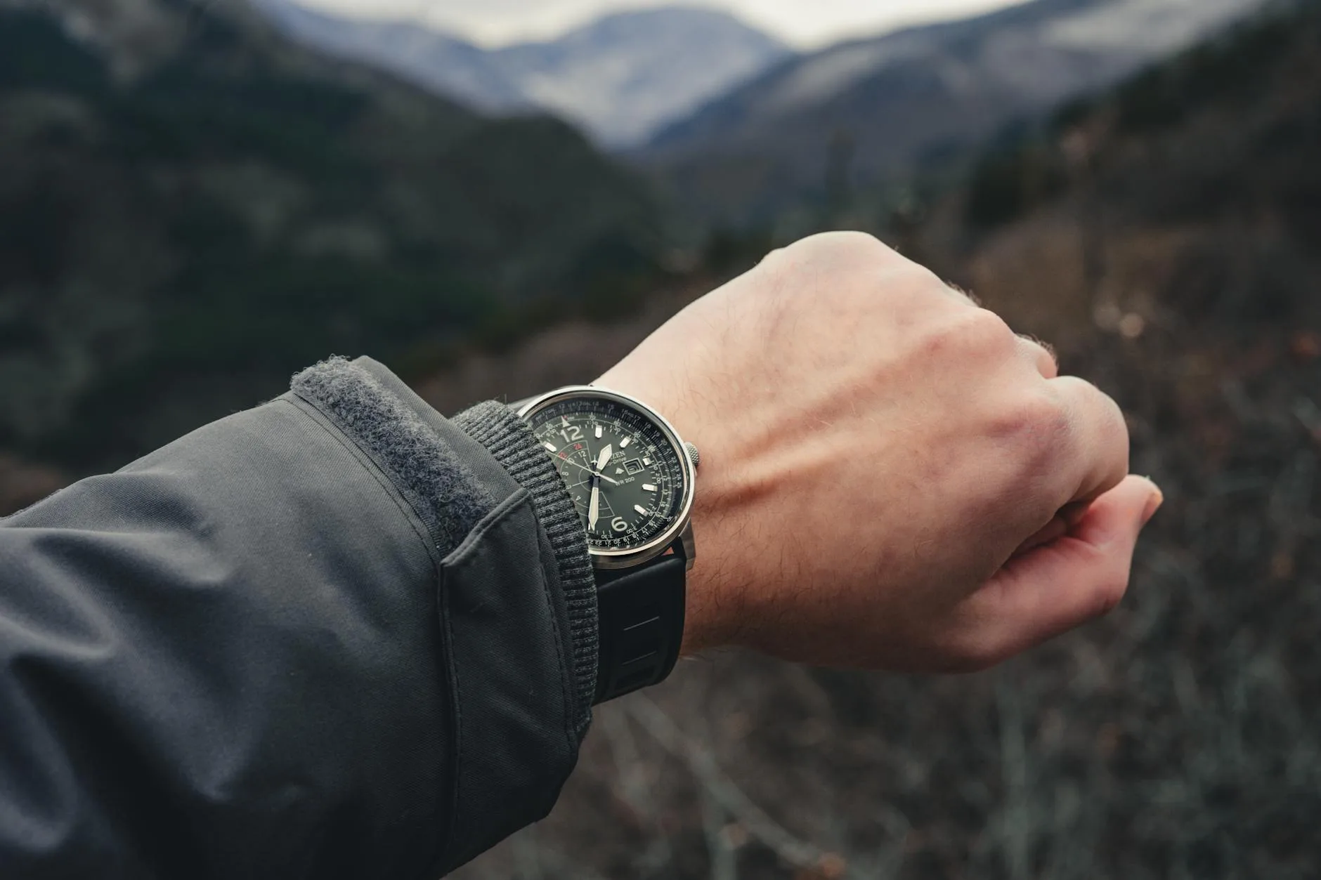 Zbliżenie zegarka na nadgarstku z górskim krajobrazem w tle
