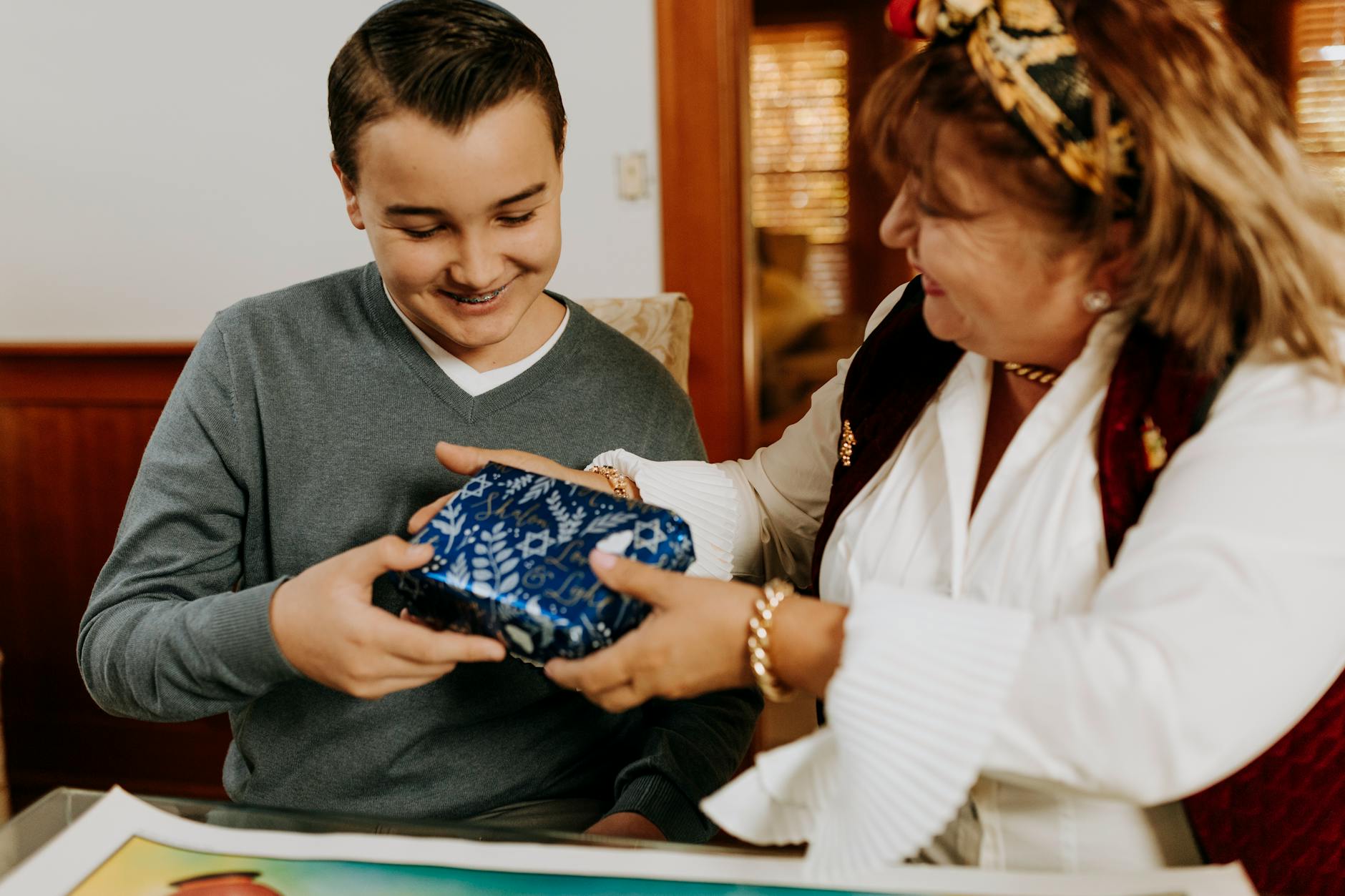 Mama wręcza nastolatkowi prezent podczas świątecznego spotkania