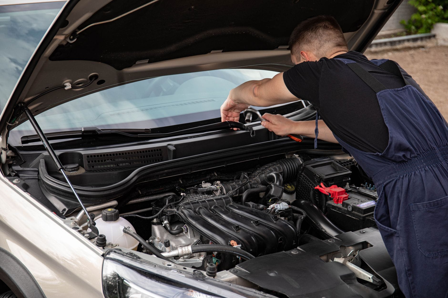 Mechanik naprawia silnik samochodu na zewnątrz w dzień