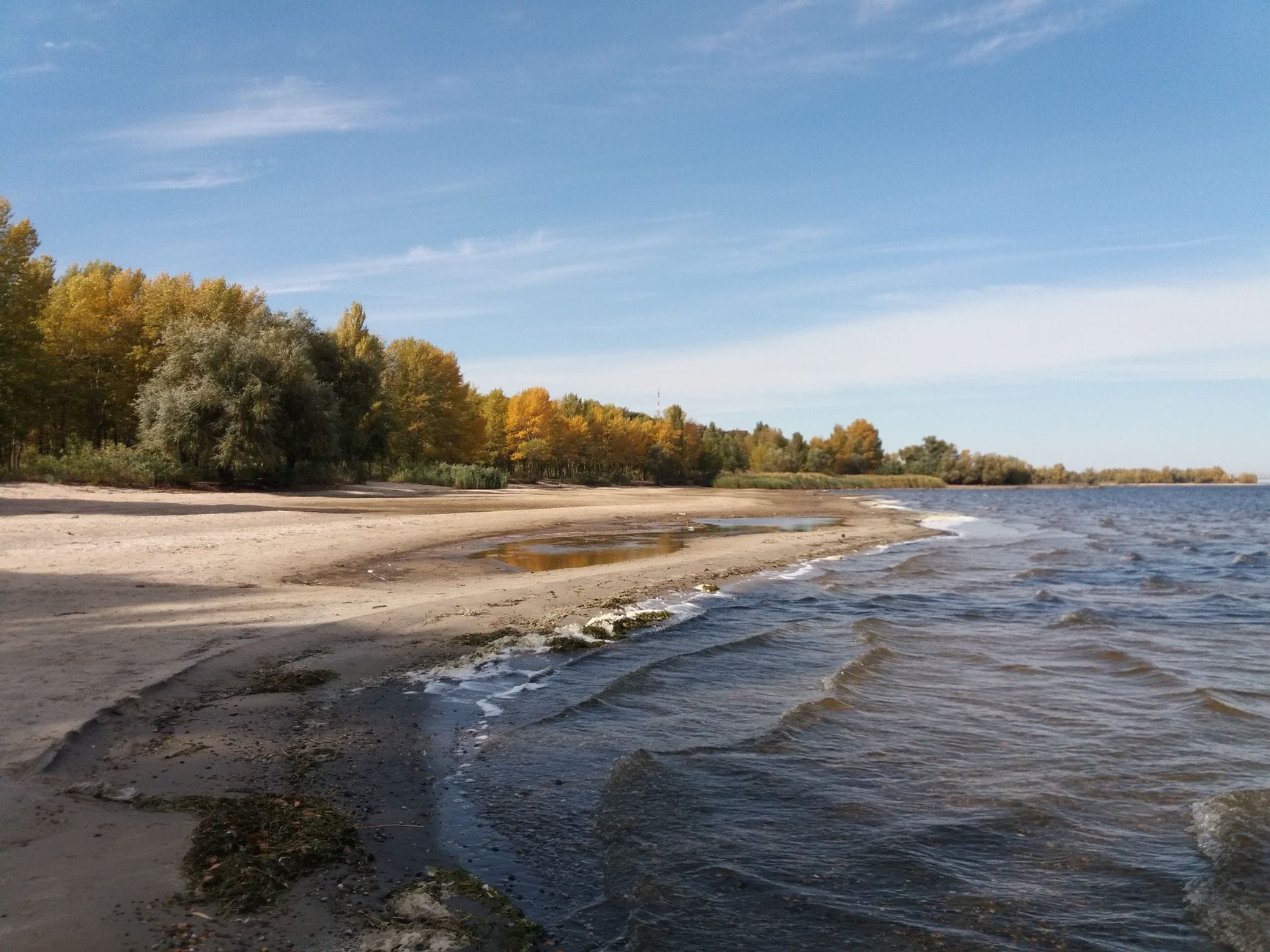 Jesienna, pusta piaszczysta plaża nad spokojną wodą