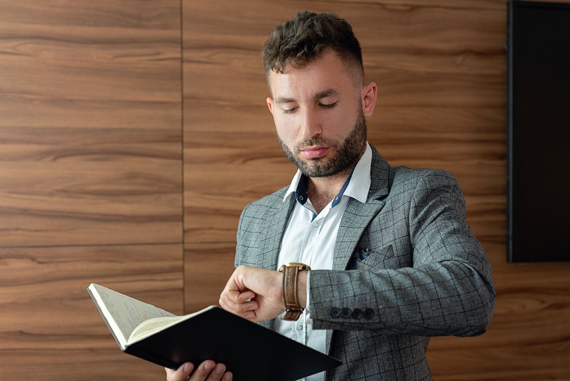 Ranking zegarków do pracy w biurze które wyglądają profesjonalnie i wytrzymują codzienne użytkowanie Młody mężczyzna w garniturze sprawdza zegarek w biurze