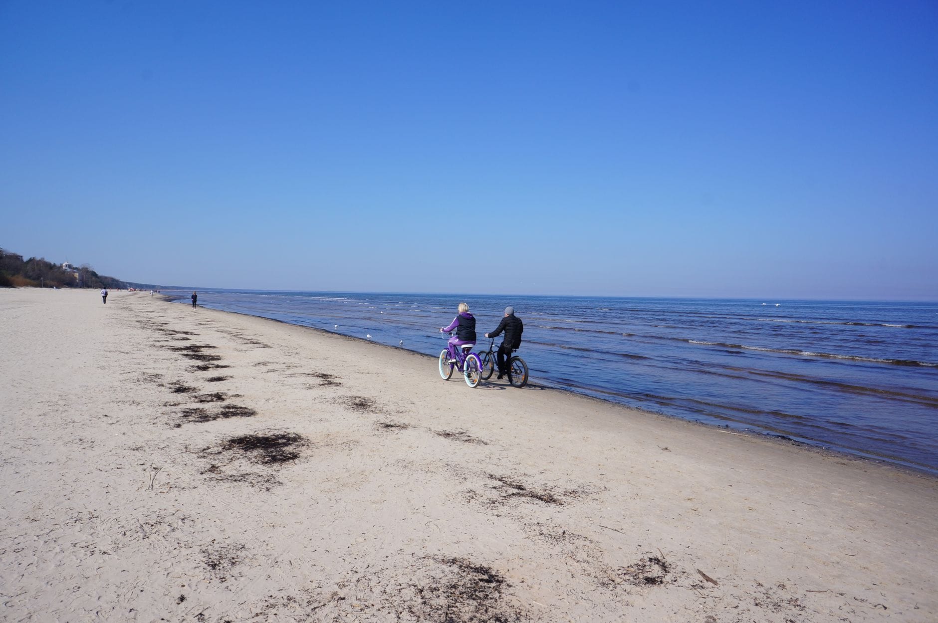 Para na rowerach jedzie wzdłuż piaszczystej plaży nad morzem
