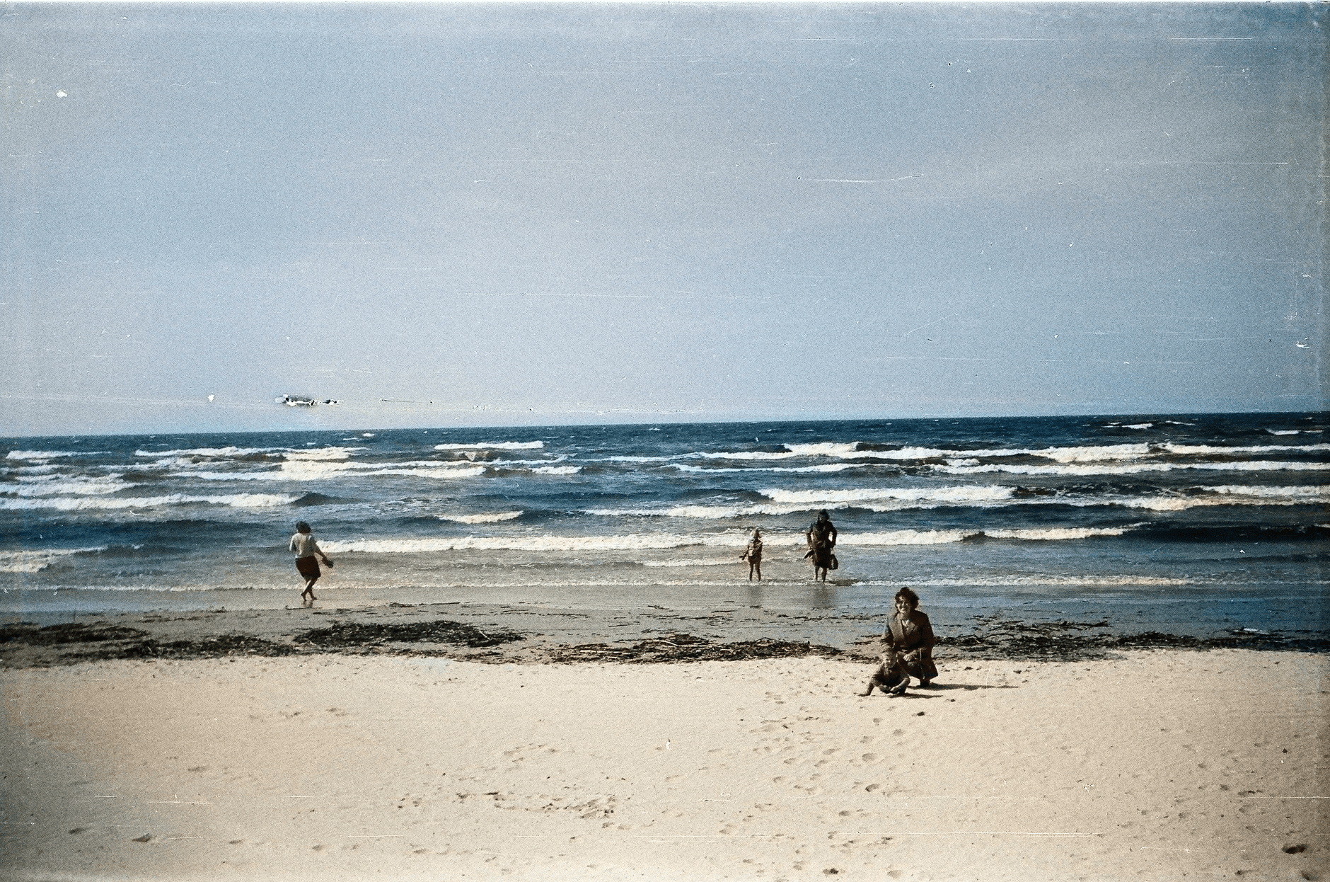 Rodzina spaceruje brzegiem morza na spokojnej, piaszczystej plaży