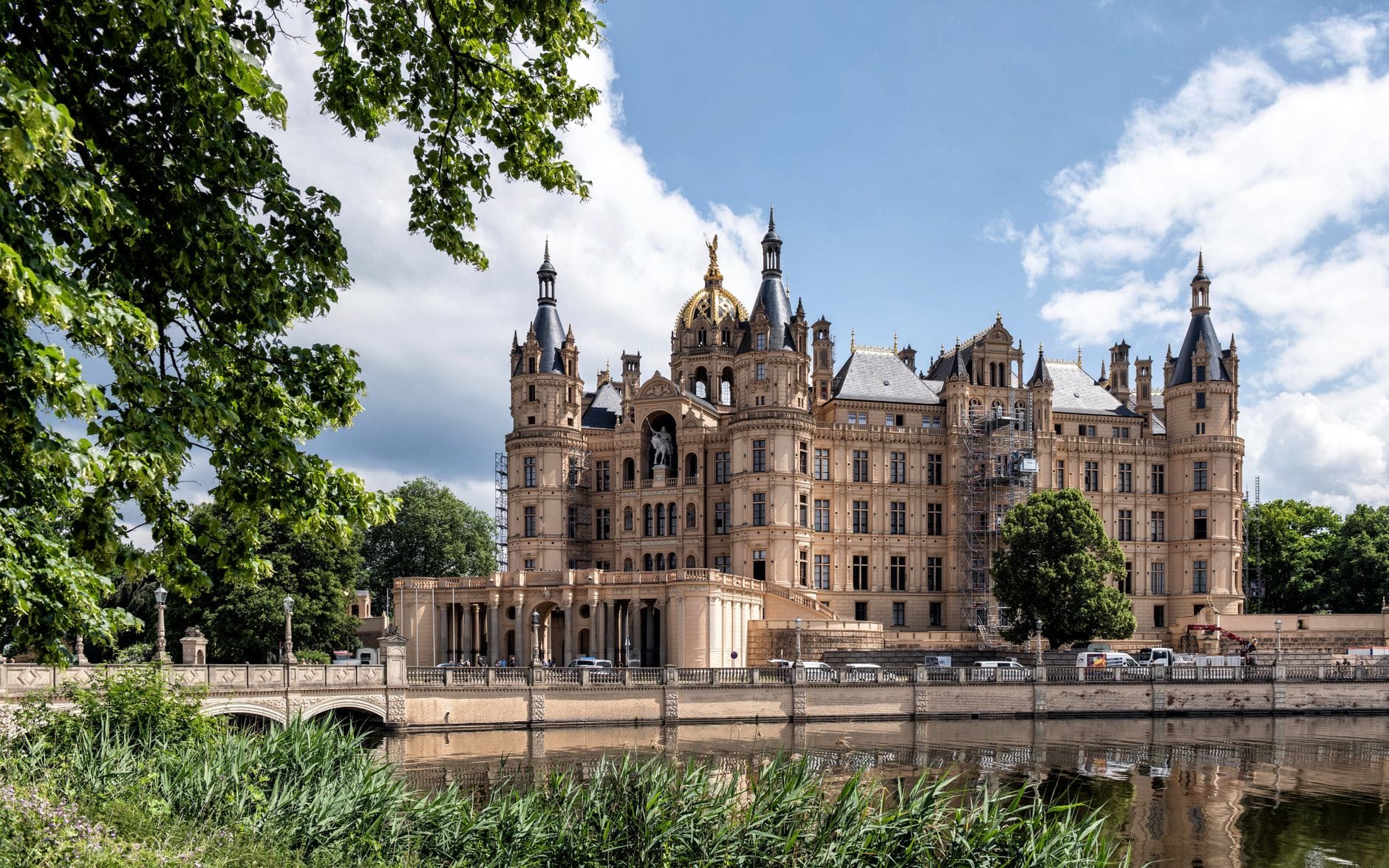 Zamek Schwerin nad jeziorem otoczony zielenią w słoneczny dzień Zamek Schwerin nad jeziorem otoczony zielenią w słoneczny dzień