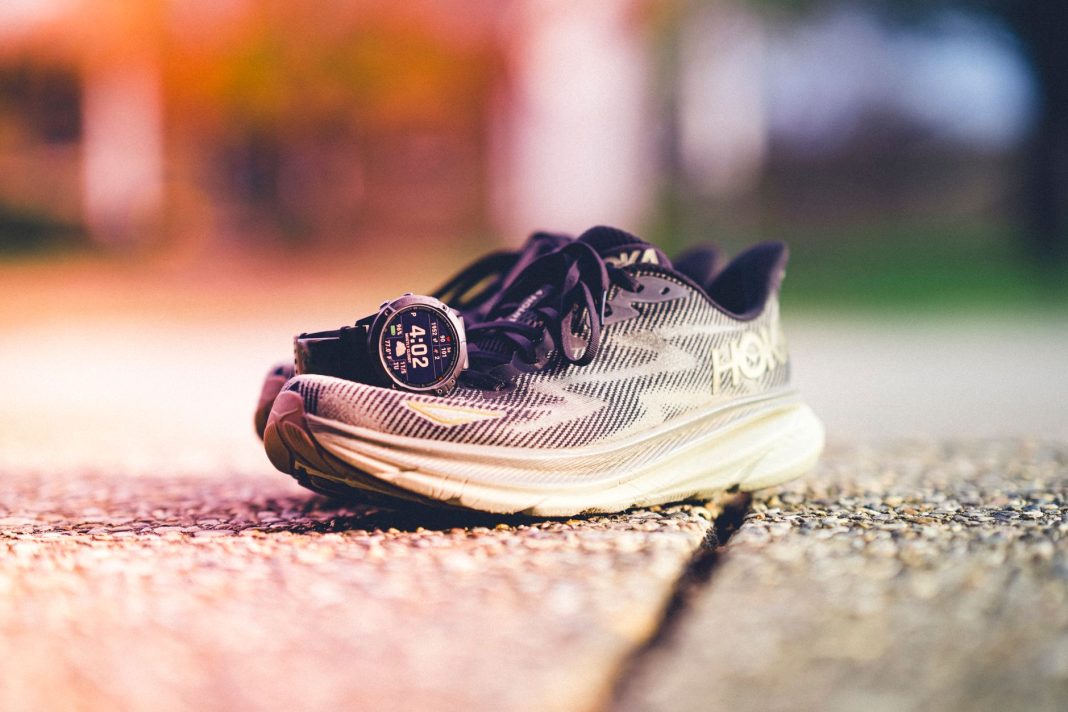 Buty biegowe Hoka i zegarek Garmin na słonecznej bieżni